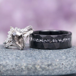 Two rings, one silver and one black, on a textured surface with a blurred purple background.