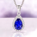 Vera Teardrop Sapphire Necklace in Sterling Silver by Aquamarise featuring a vivid blue pear-shaped lab-grown sapphire surrounded by sparkling white accents on a polished silver pendant.