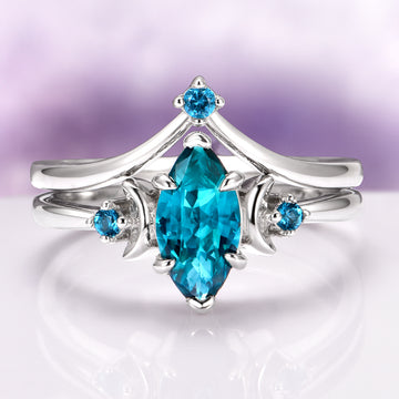 Teal Sapphire Crescent Moon Ring Set in 14K White Gold featuring a marquise-cut teal sapphire center flanked by crescent moon and small round teal sapphires, crafted by Aquamarise Gold from nature-inspired and fantasy engagement collections.