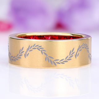 Front view of the brushed gold titanium band showing the laser-etched laurel vine and the red garnet inside