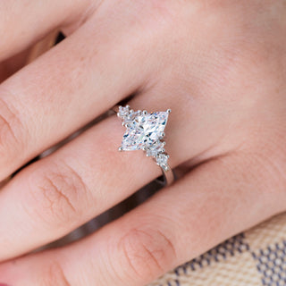 White gold ring with marquise cut diamond center stone and accents on hand over light background 
