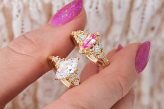 Hand holding two marquise cut gold rings on a light background 
