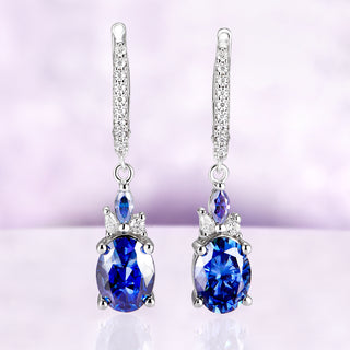 Blue Moissanite Earrings Midnight Blue Drop Earrings over a light purple background 