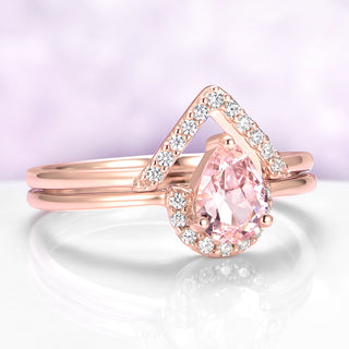 Rose gold ring with a pear-shaped pink gemstone on a light purple background