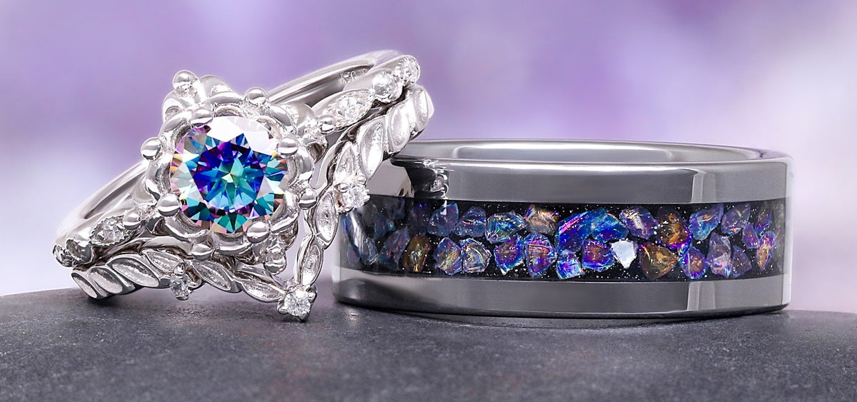 Two rings with colorful gemstones on a gray surface with a purple gradient background