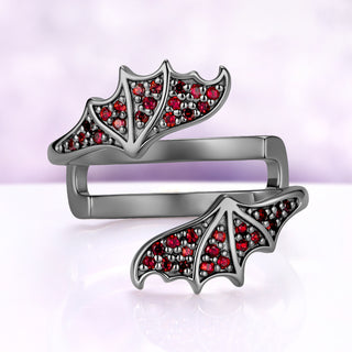 Bat wing wrap band shown on its own, both garnet pavé wings spread from the black ruthenium band