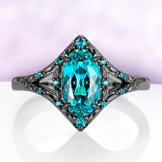 Nerida Lab-Grown Paraiba Blue Spinel Engagement Ring in Black Ruthenium by Aquamarise, oval neon blue spinel in a kite-shaped frame of engraved leaves