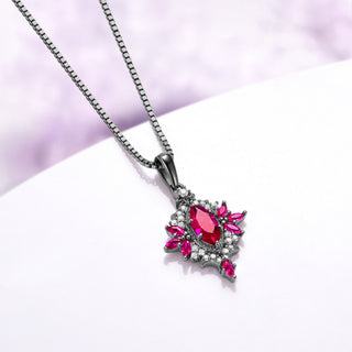 Angled view of the Nightbriar ruby pendant showing the red marquise rays radiating from the milgrain frame and the tapered bail on the box chain