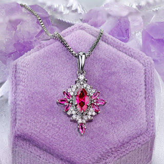 Nightbriar lab-grown ruby pendant necklace on a lilac velvet ring box, red marquise rays around the milgrain frame