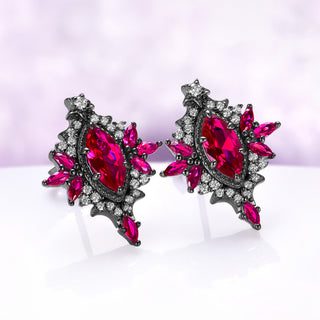Angled view of the Nightbriar ruby stud earrings showing the deep red marquise rays, cubic zirconia halo and the star set above the frame