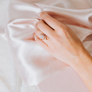 Hand with a rose gold diamond ring set on a pink background