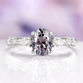 Diamond ring with a purple gemstone on a white surface with a blurred purple background
