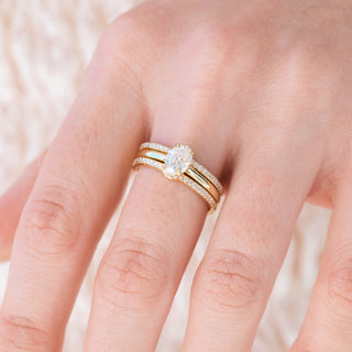 Yellow gold engagement ring set with oval cut diamond center stone and accents on hand over a light background 