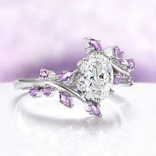 Silver ring with pear-shaped diamond and purple gemstones on a light purple background