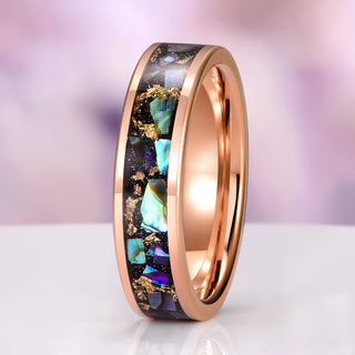 Rose gold ring with multicolored stone inlay on a white surface with a purple gradient background