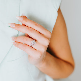 Hand with a floral design diamond ring on a light background