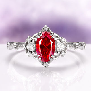 Silver ring with a red gemstone on a reflective surface with a blurred purple background