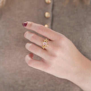 Yellow gold leaf engagement ring with oval-shaped morganite and diamond accents displayed in hand against warm brown backdrop