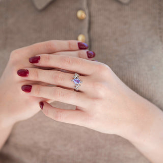 Sterling silver leaf engagement ring with oval-shaped alexandrite displayed in hand against warm brown backdrop