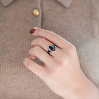 Black coffin-cut sandstone engagement ring with diamond and sandstone accents paired with a chevron wedding band displayed in hand against a warm brown backdrop