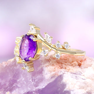 Gold ring with a purple gemstone on a pink crystal background