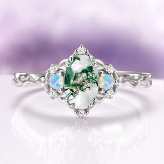 Silver ring with a green gemstone and opal-like stones on a light purple background