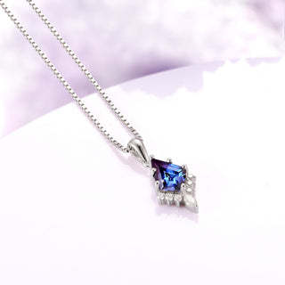 Silver necklace with a blue gemstone pendant on a light purple background