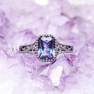 Radiant Cut Alexandrite Engagement Ring in Black by Aquamarise, a radiant-cut colour-change alexandrite in a vintage milgrain setting on lilac crystals.