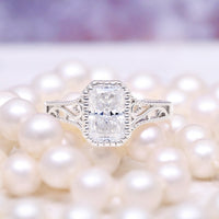 Lab Grown Diamond Engagement Ring in 14K White Gold (IGI Certified) by Aquamarise Gold, featuring an intricate filigree band surrounding a radiant cut diamond on a soft pearl background.