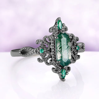 Angled view of the Ravenna moss agate ring, showing the beaded scrolls, the marquise simulated emerald at each end and the looped shoulders