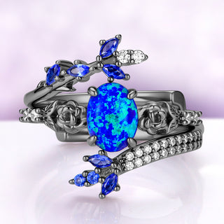 Opal engagement ring set in black ruthenium — oval lab-created blue opal between sculpted roses with a sapphire pavé wrap band by Aquamarise