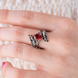 White gold ring with oval cut lab grown ruby center stone and black onyx accents on hand 