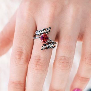 White gold ring with oval cut lab grown ruby center stone and black onyx accents on hand 