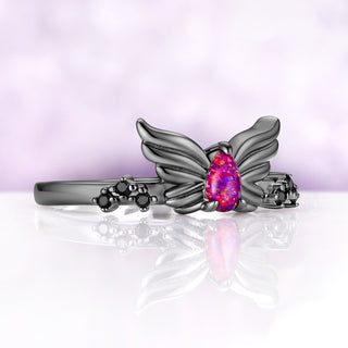 Angled view of the Selene wing ring, showing the feather detail on the wings and the magenta flashes in the opal