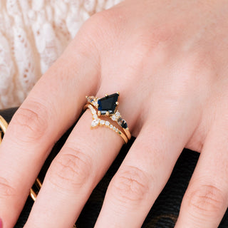Yellow gold engagement ring set with kite cut natural onyx center stone and Herkimer diamond accents on hand over a light background 