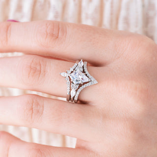 Silver engagement ring set with kite cut diamond center stone and accents on hand over a light background 