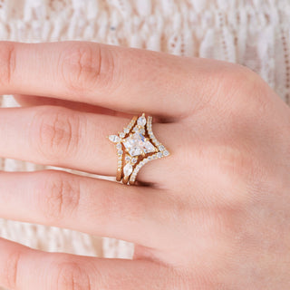 Yellow gold engagement ring set with kite cut diamond center stone and accents on hand over a light background 