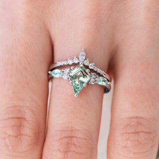 White gold ring with kite cut lab grown light green sapphire center stone and diamond accents on hand over a light background 
