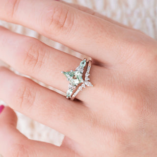 White gold ring with kite cut lab grown light green sapphire center stone and diamond accents on hand over a light background 