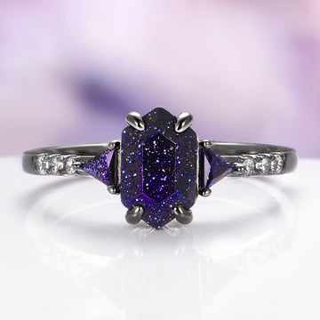 Ring with purple gemstone and diamond accents on a white surface with a blurred purple background