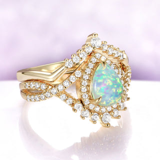 Gold ring with a teardrop-shaped opal stone on a light purple background