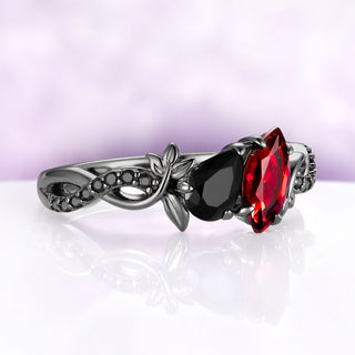 Angled view of the garnet and onyx toi et moi ring, showing the twisted vine band set with a row of small round black onyx