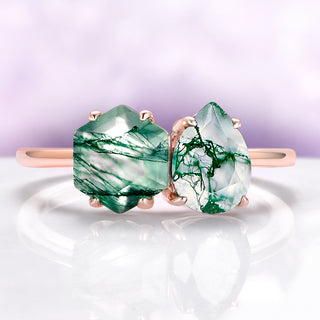 Green gemstone earrings with rose gold setting on a white and purple gradient background