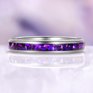 Silver ring with purple embedded stones on a reflective surface with a blurred purple background