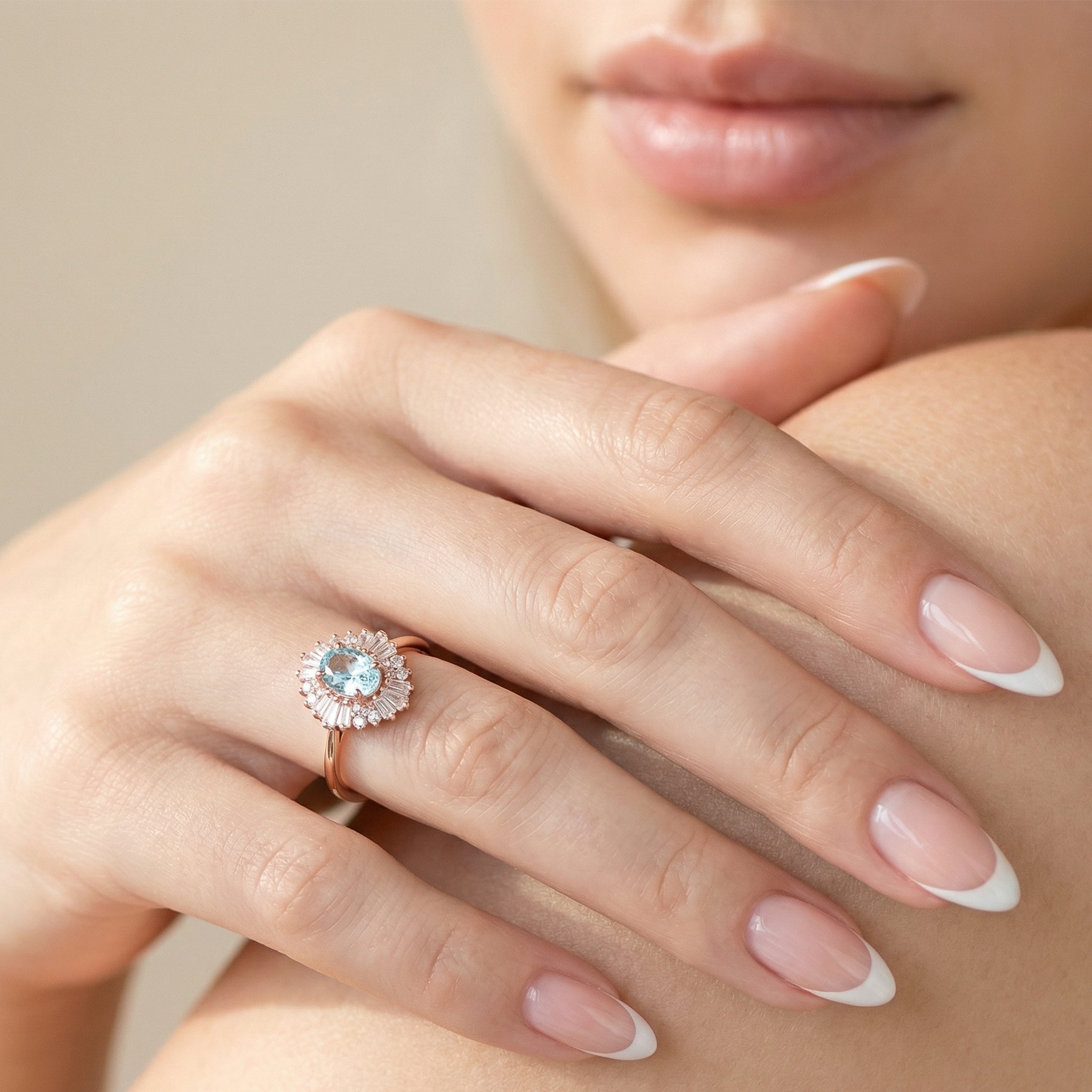 Model wearing a vintage-style ring with an oval aquamarine framed by tapered baguettes and round accents