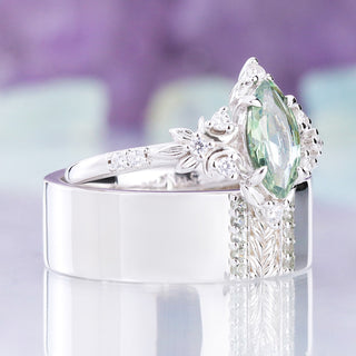 Angled view of the Viridian green tourmaline couples set, her ring resting on his 8mm leaf band