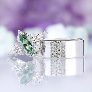 Viridian green tourmaline couples ring set on a reflective surface showing both sterling silver rings mirrored below