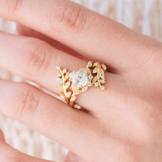 Yellow gold engagement ring set with teardrop cut diamond center stone and accents on hand over a light background 