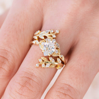 Yellow gold engagement ring set with teardrop cut diamond center stone and accents on hand over a light background 