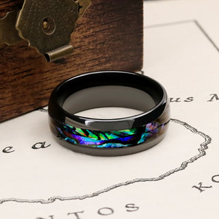 Polished black tungsten men's band with an iridescent abalone shell inlay, styled on a vintage map